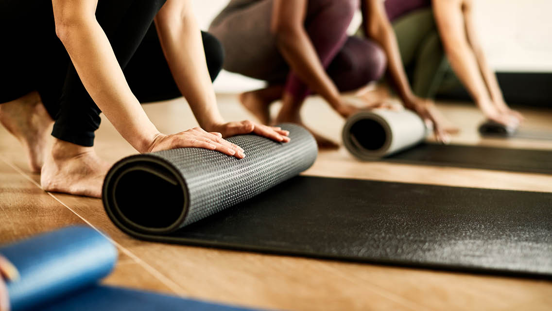 people roll exercise mats in a fitness studio