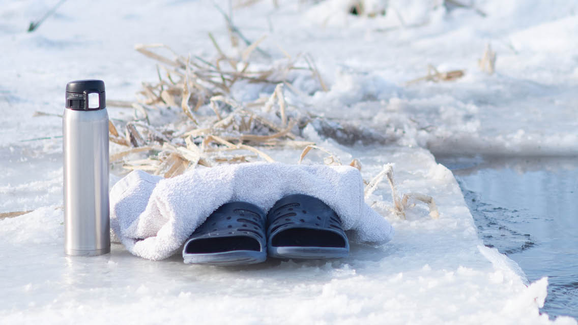a pair of shoes, thermos and towel sit on an ice covered lake