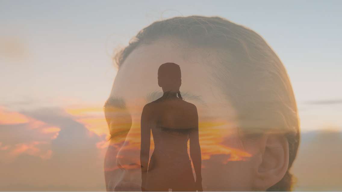An image of a woman's silhouette over a woman's head with her eye's closed and a sunset in the background.