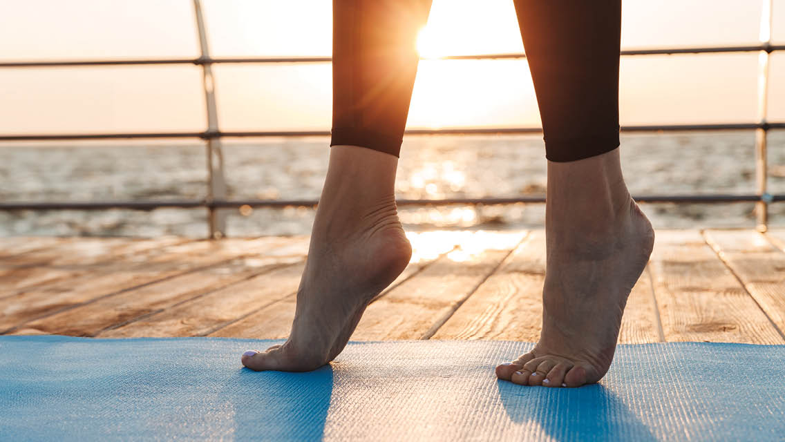 a person stands on their toes on a yoga mat