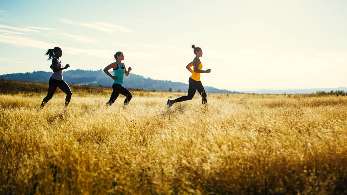 women run through a field