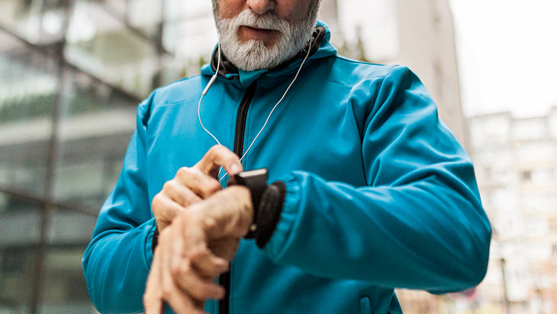 a man with a gray beards checks in smart watch