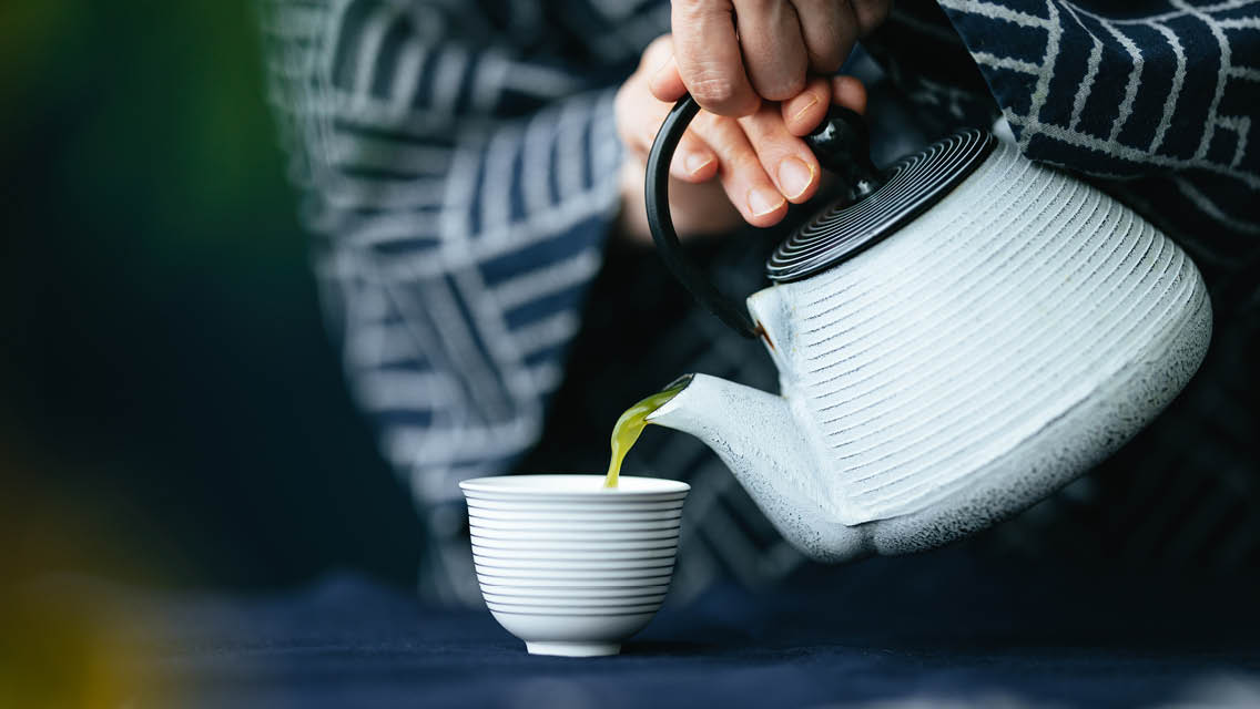 a person pours a cup of green tea