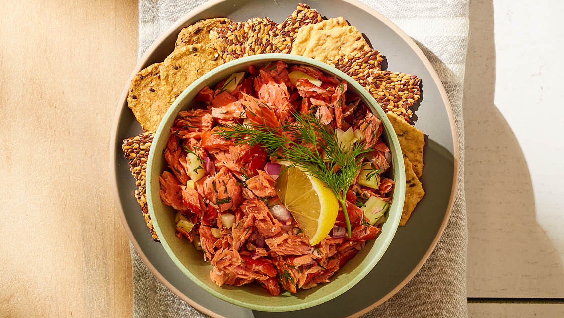 a bowl of smoked salmon salad served with crackers
