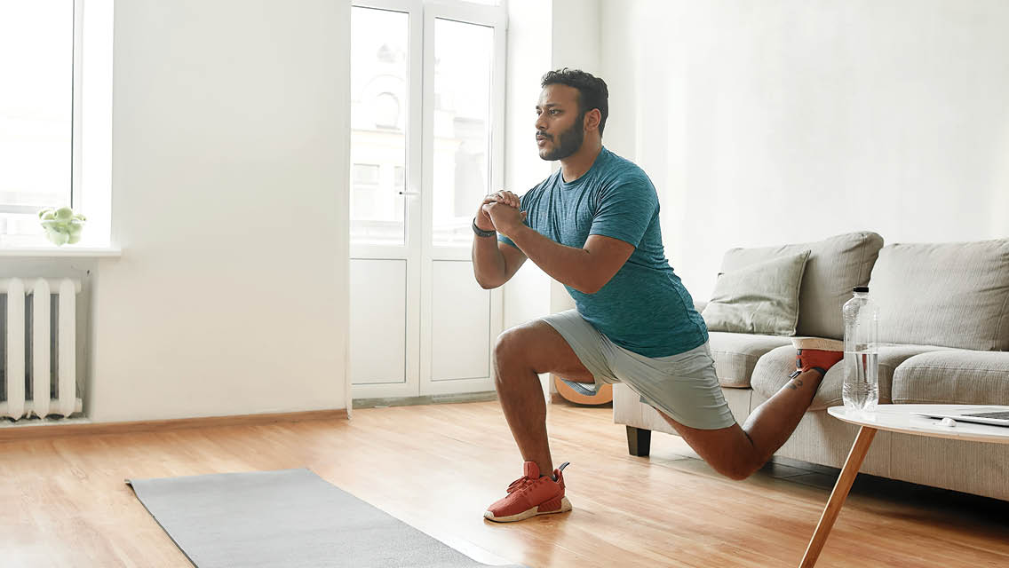 a man performs a Bulgarian squat in his living room