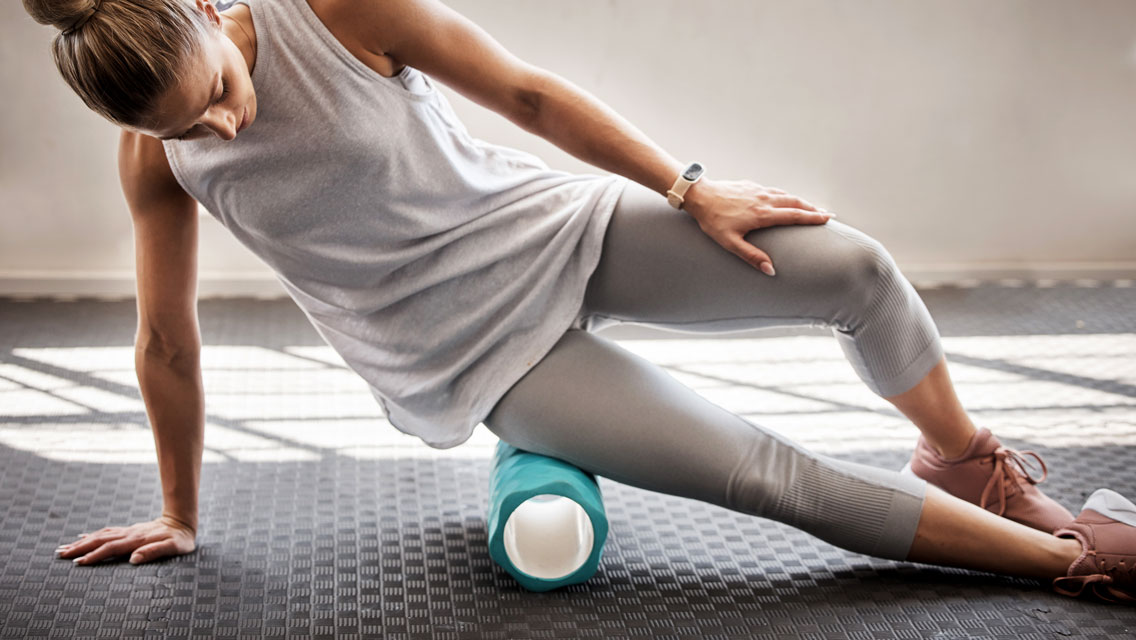 a woman foam rolls her IT band