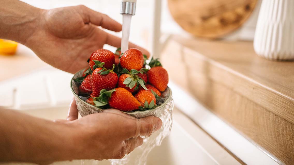a person washes strawberries