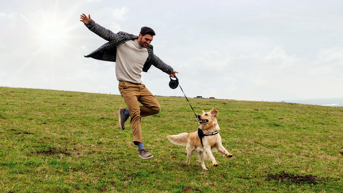 a man skips down a hill with his dog