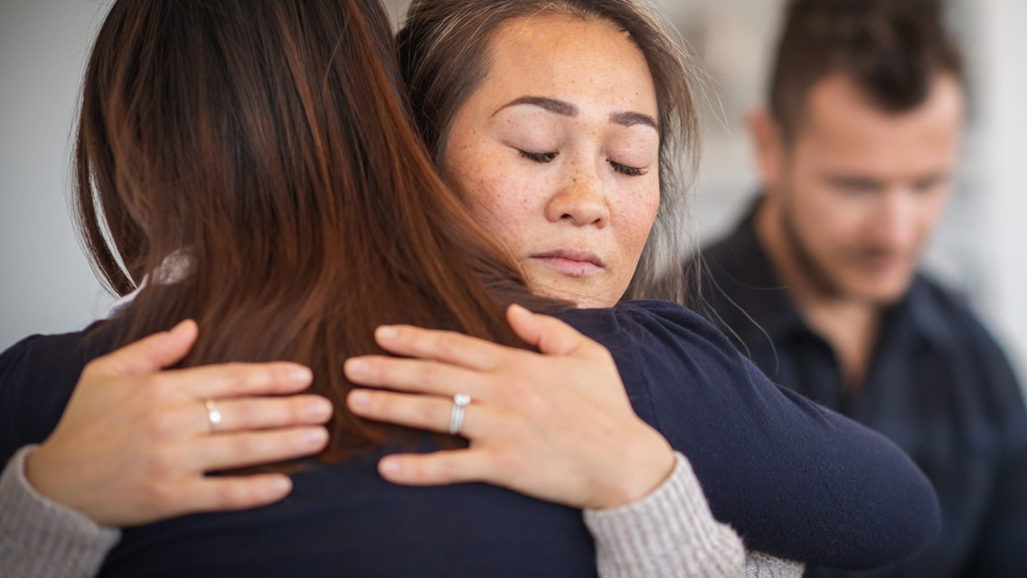 people hugging each other and a sad person in the background