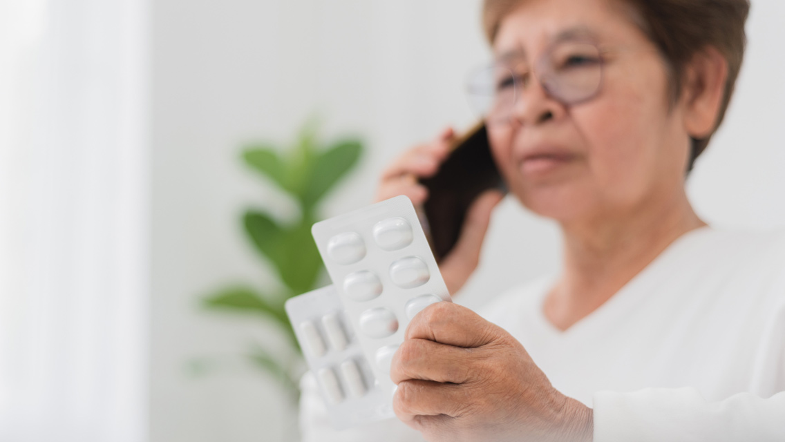 a woman talks on the phone while holding a pill pack