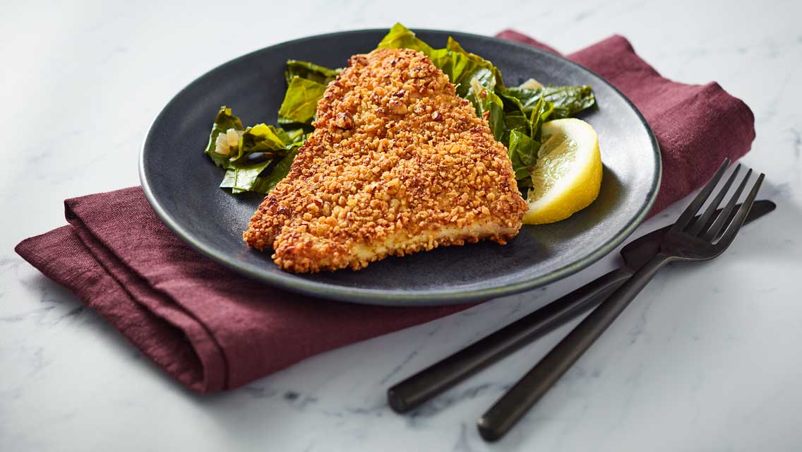 a plate of low country pecan crusted red snapper and collard greens