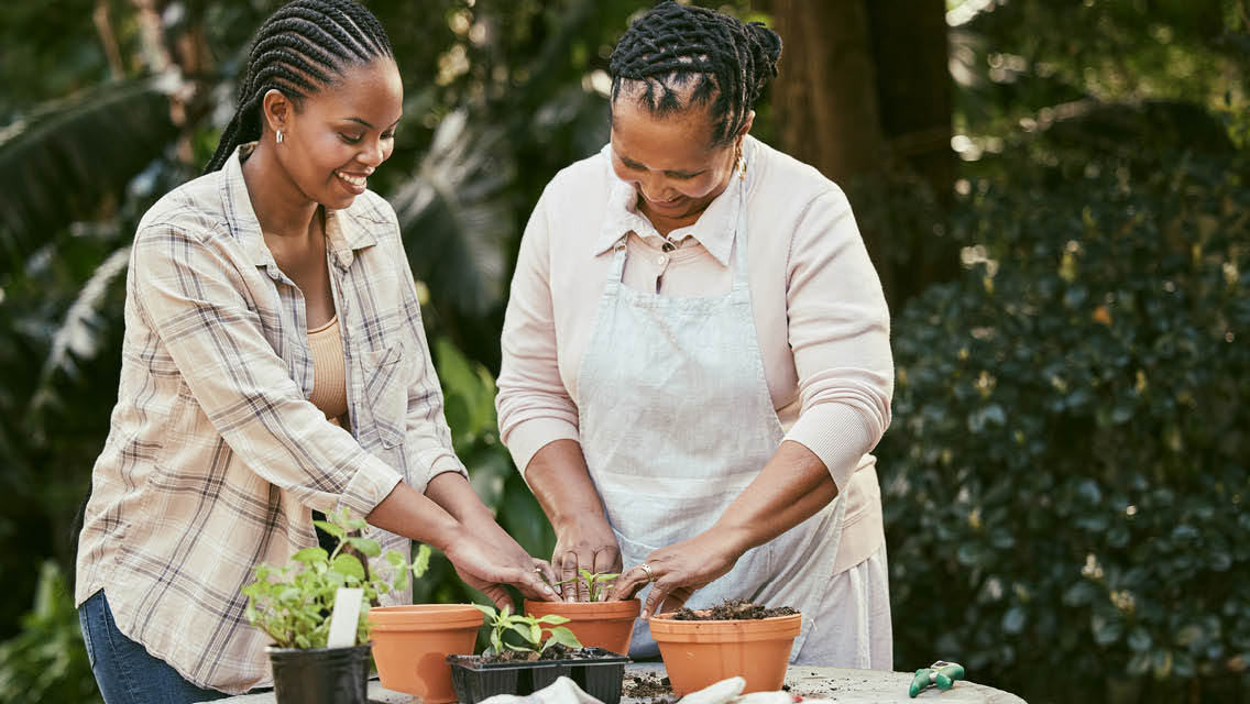 a mother and daughter work together planting in pots