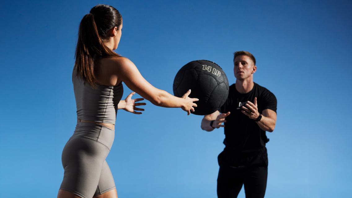 Two people passing a medicine ball during a workout