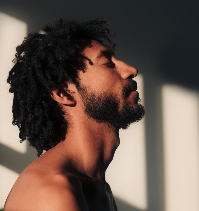 A man with his eyes closed looking peaceful in a lighted room.