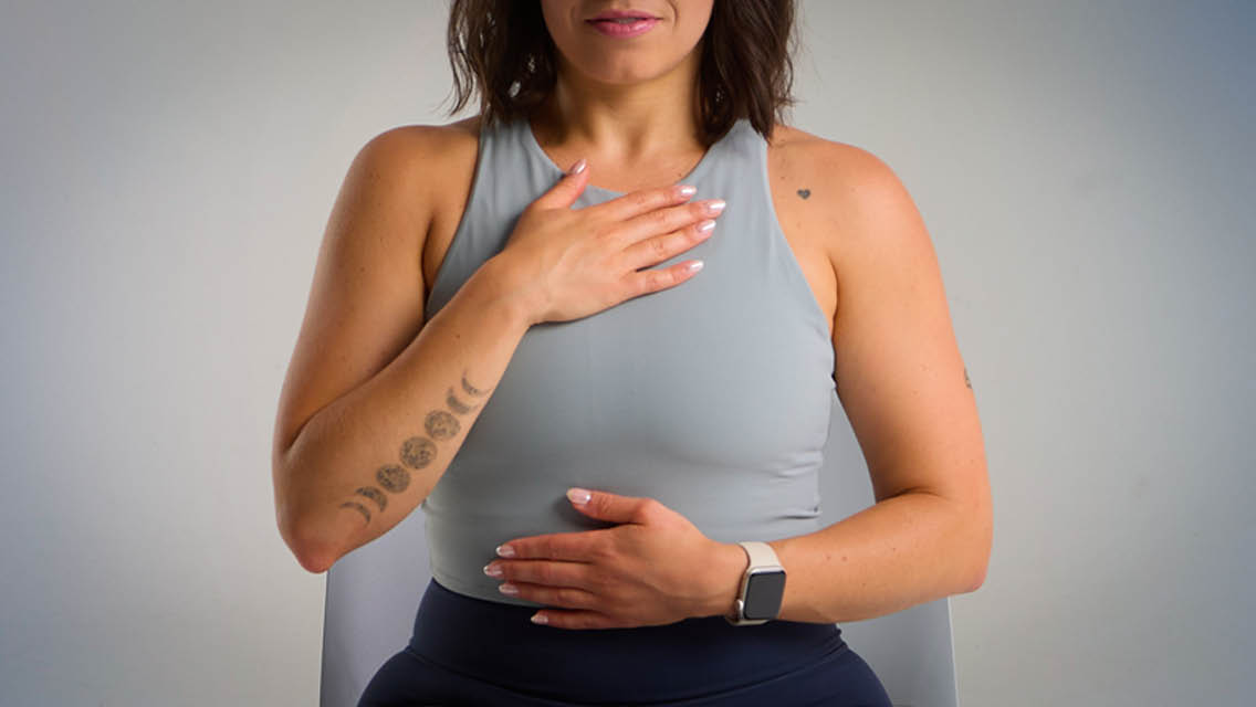 a woman breathing with one hand on her heart and the other on her belly