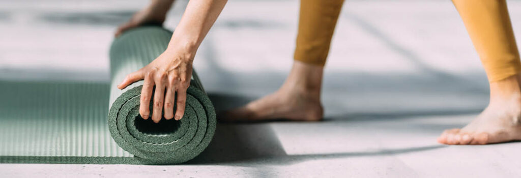 a person rolls a yoga mat.