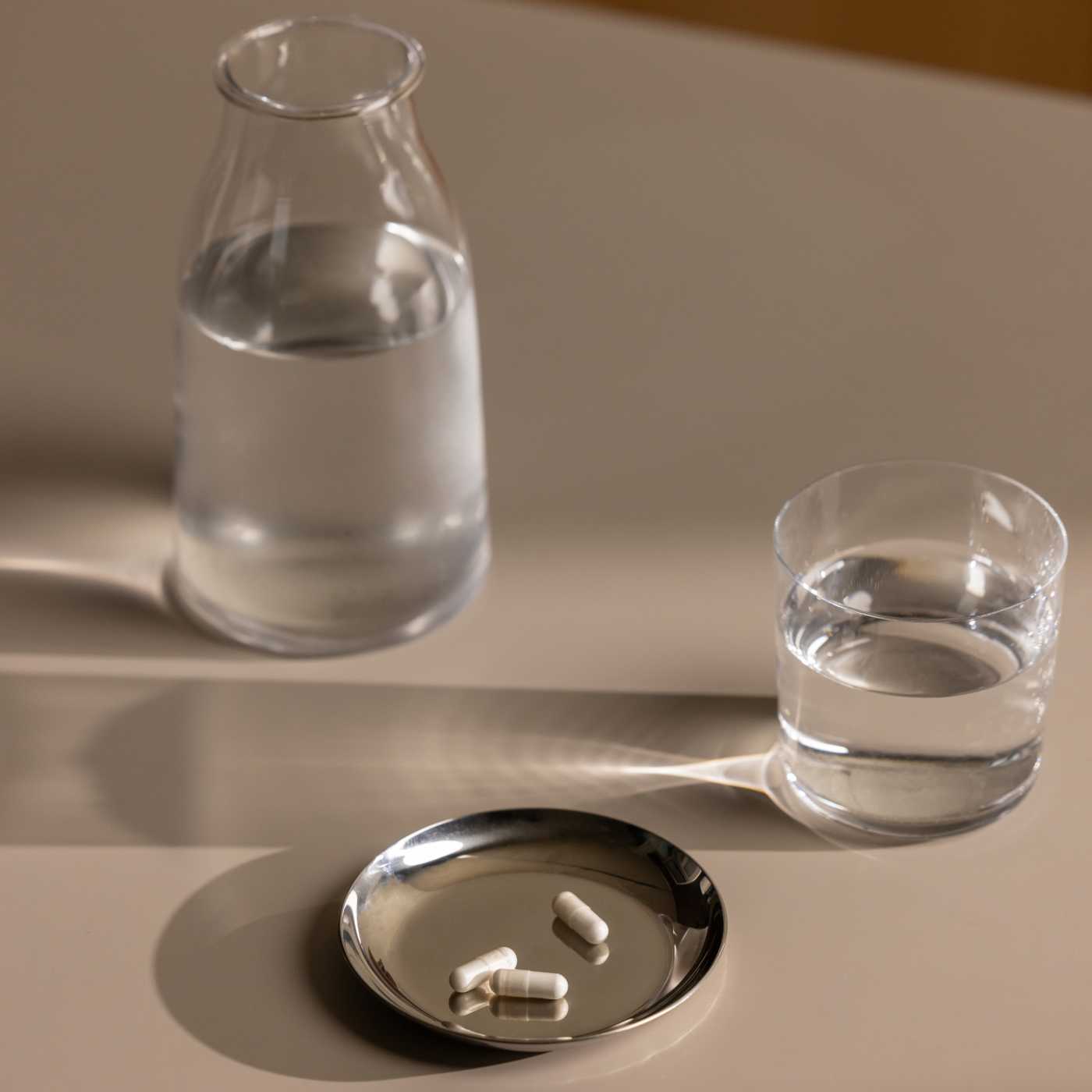 capsules in dish next to pitcher of water