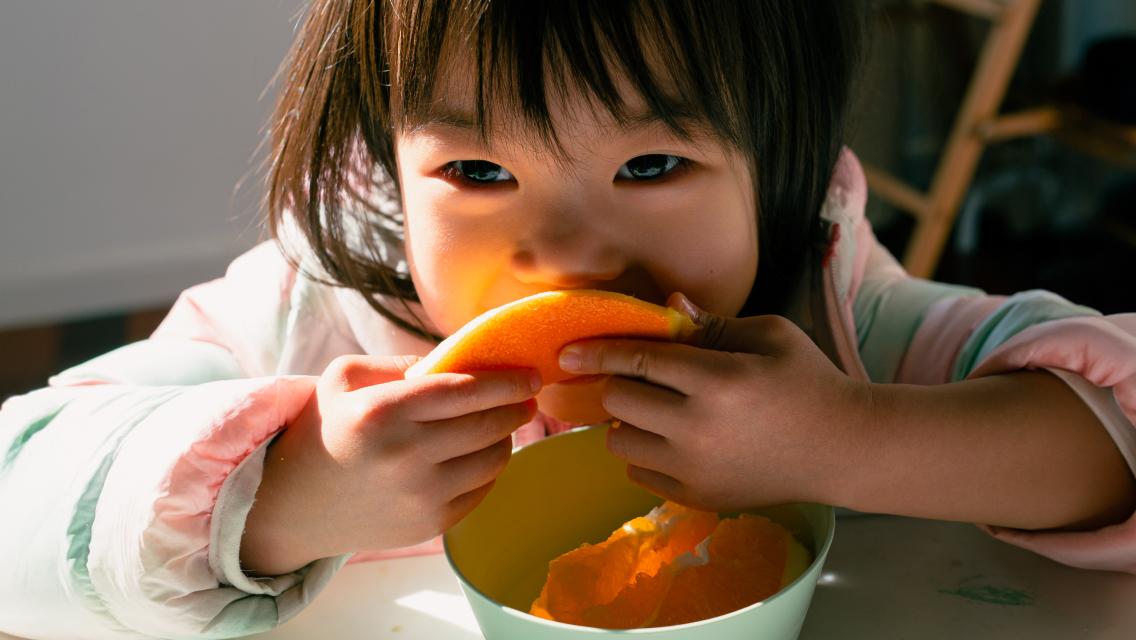 child eating an orange