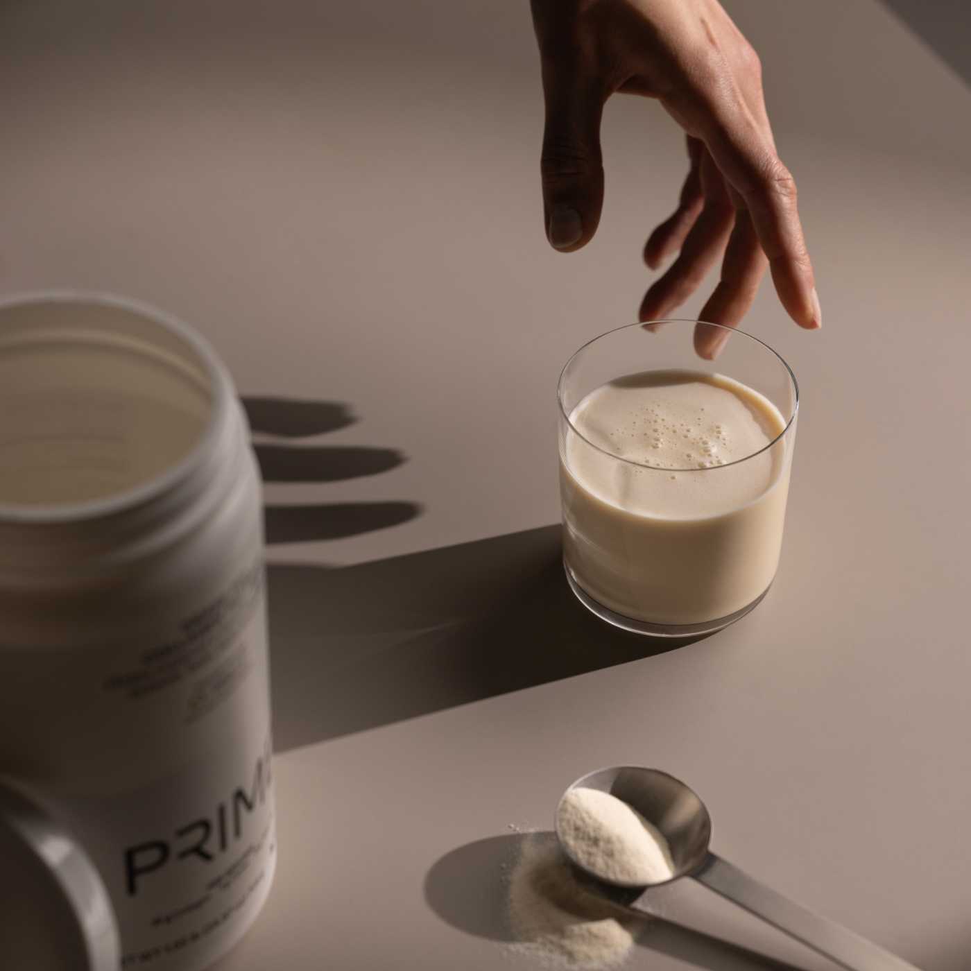 hand reaching for a glass with prime collagen in it