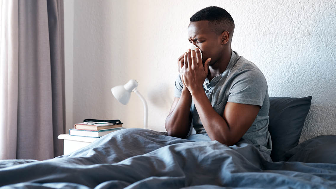 a man blows his nose in bed