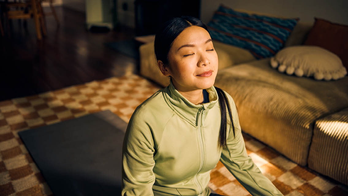 a woman meditating with sun shining on her