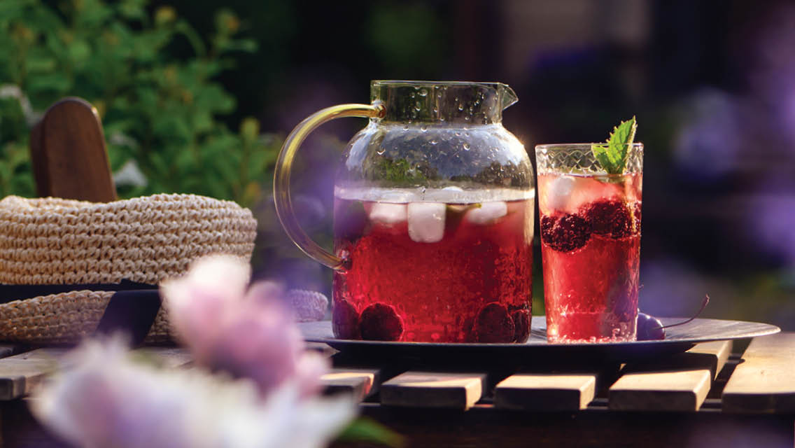 a pitcher of a red beverage and glass