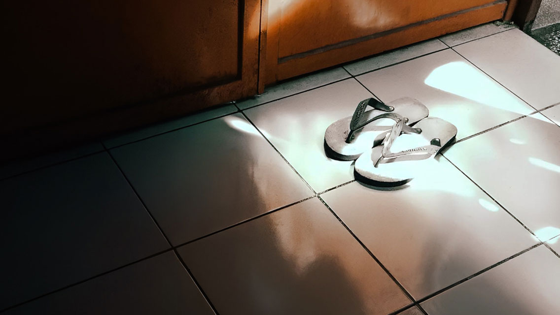 a pair of flip flops sit on a tile floor next to a locker