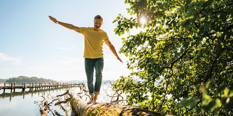 a man walks on a downed tree