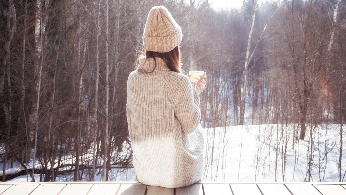 a woman hits outside drinking a warm beverage