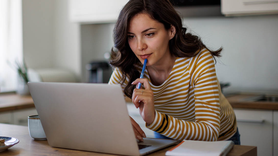 a woman looks thoughtfully at her computer