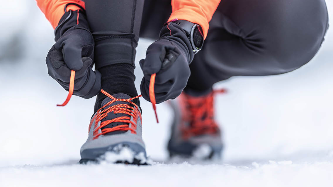 a person ties their winter running shoes