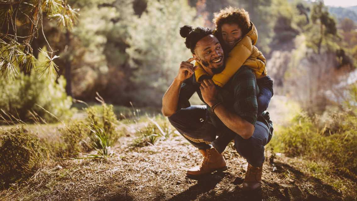 man with child on his back in nature