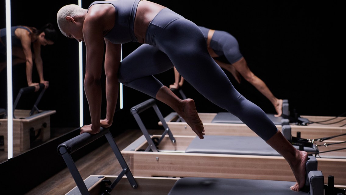 Two women performing a move from CTR on a reformer in a fitness studio.
