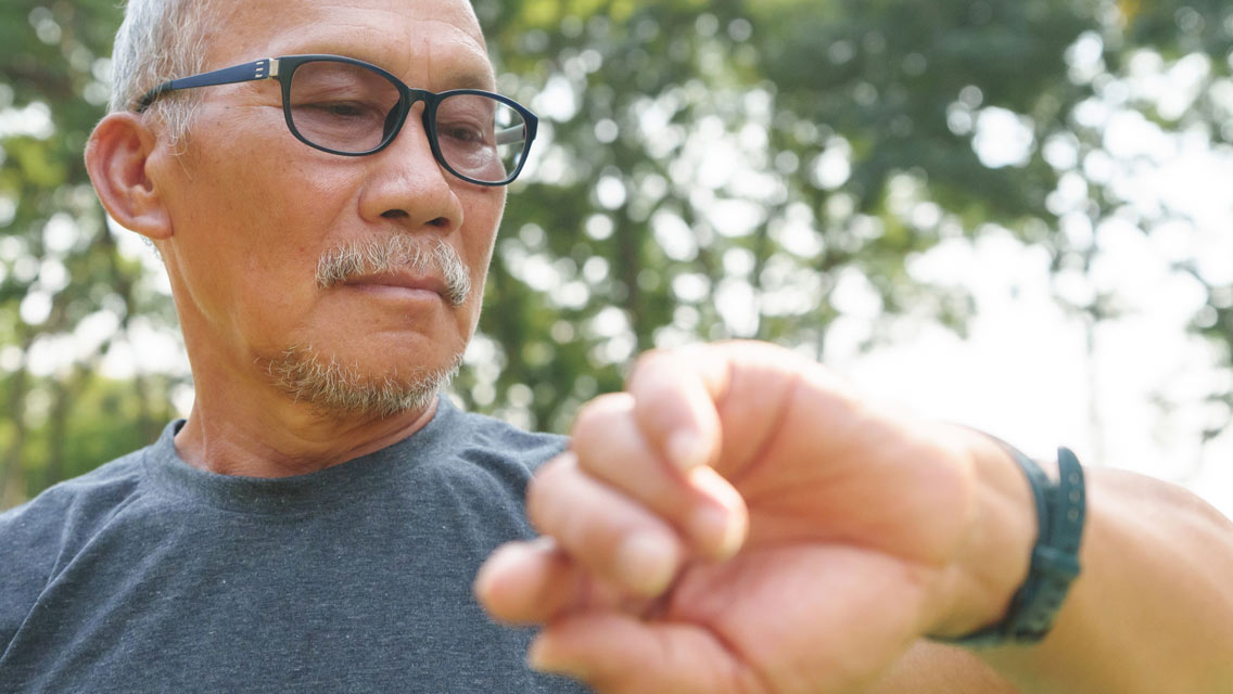a senior man looks at his smartwatch
