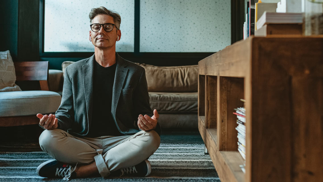 a man in causal business attire sits meditating