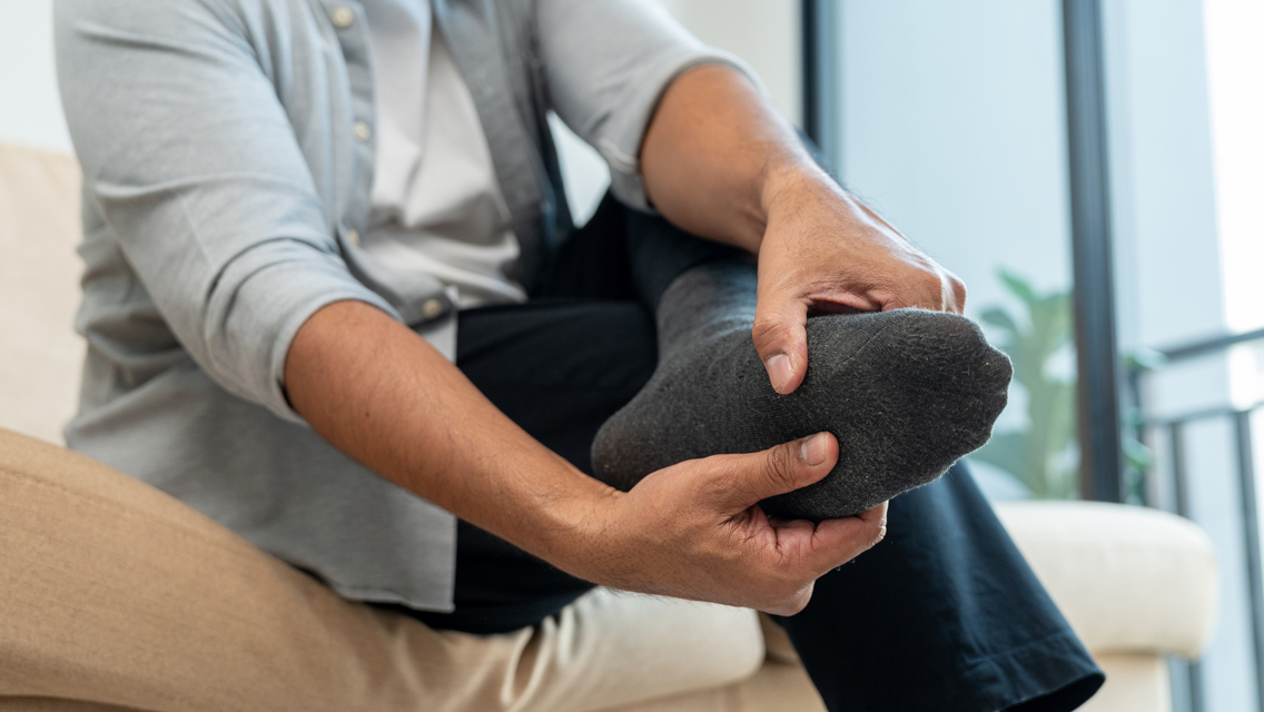 a man holds his foot while sitting on a couch
