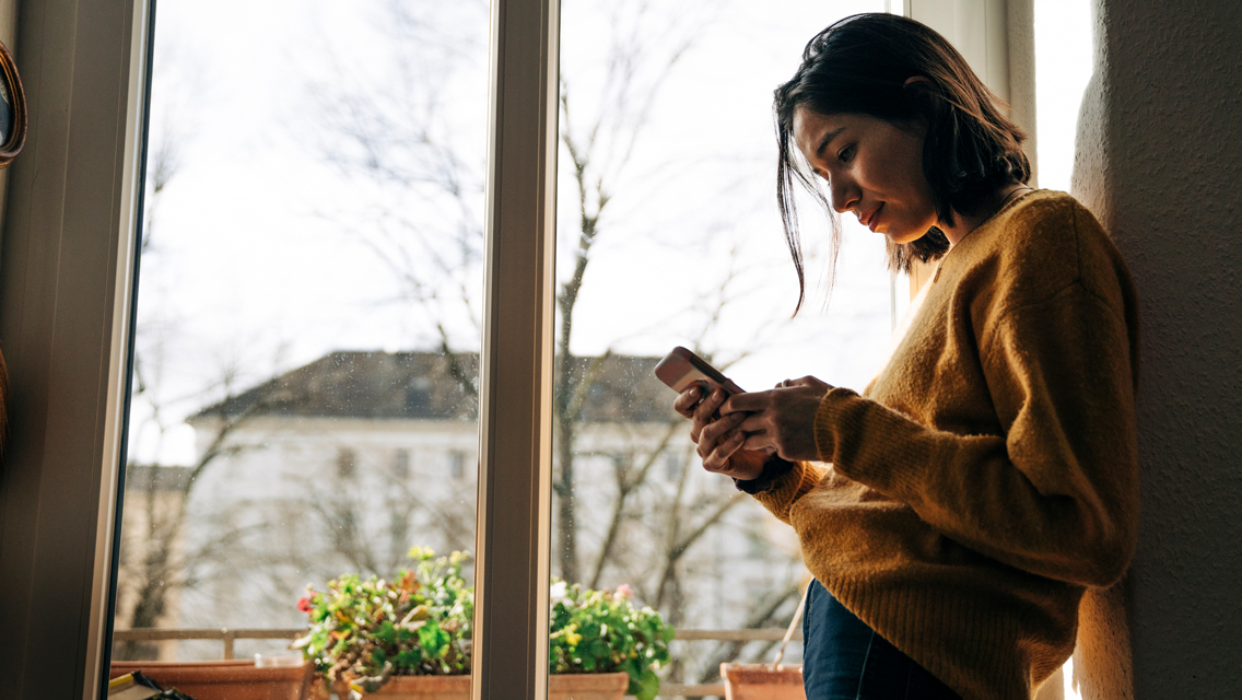 a woman hunches while looking at her cell phone