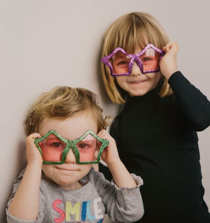 Two young kids wearing star sunglasses.