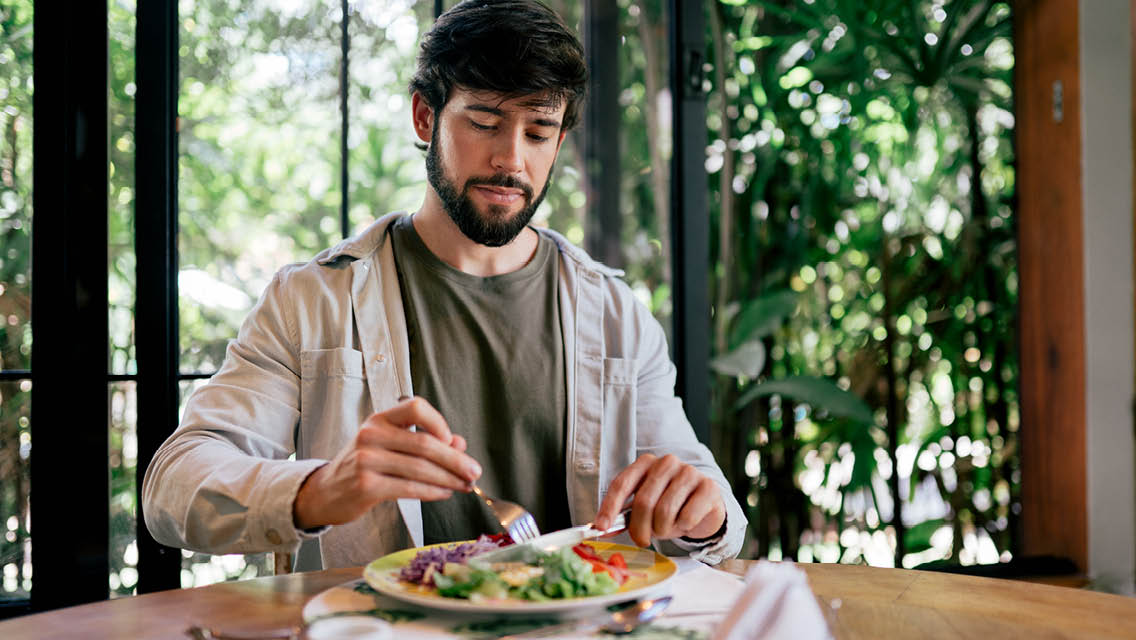 a man cuts fresh vegetables at his dinner table