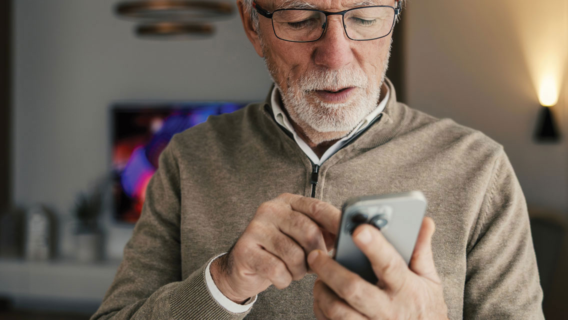 a senior man uses his smartphone