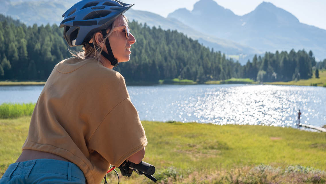 a woman stops to look at a mounting lake while biking
