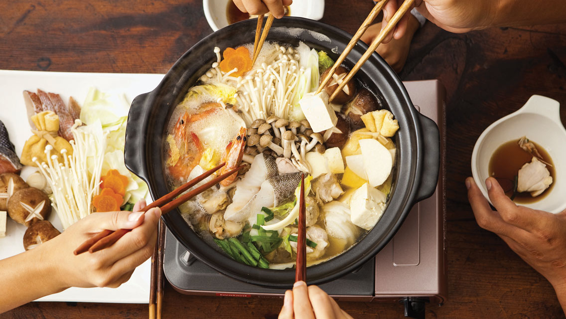 people use chopsticks to serve food from a pot
