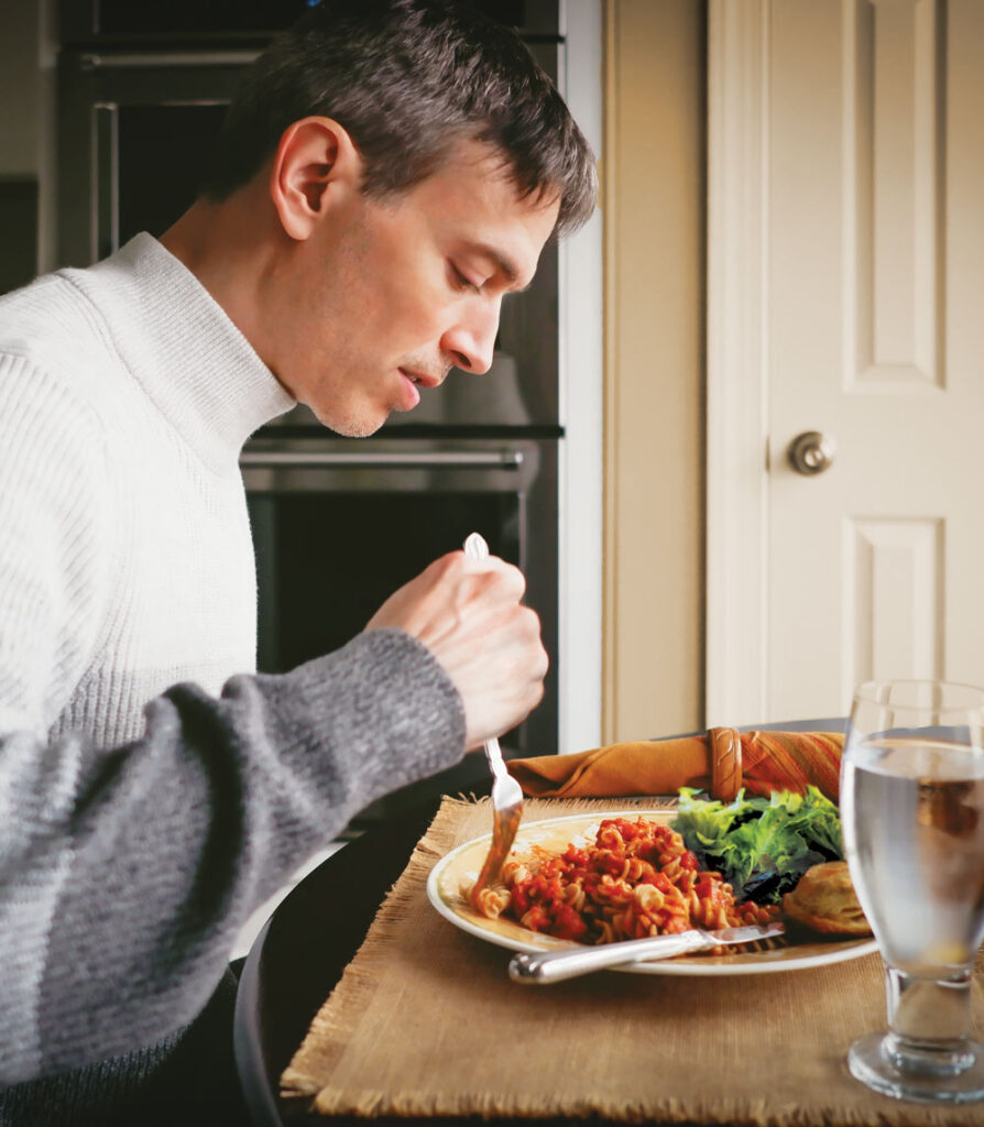 a man eats his dinner alone at his kitchen table