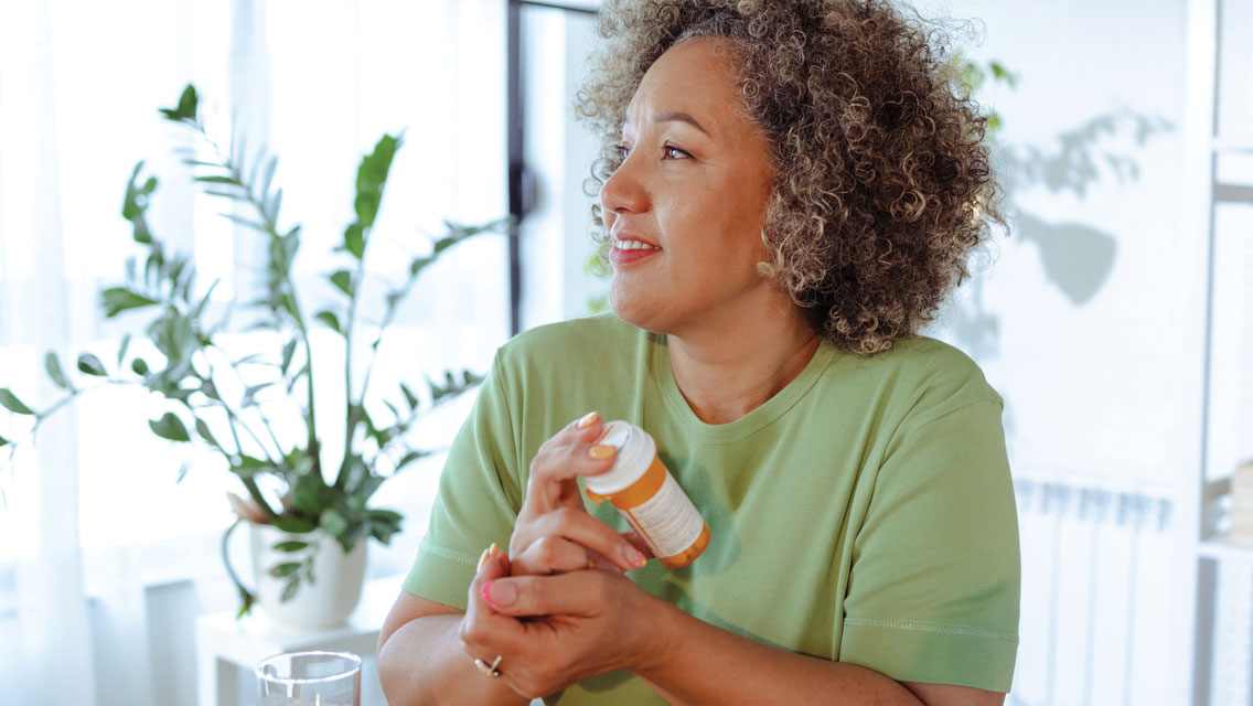 a middle aged woman holds a bottle of pills