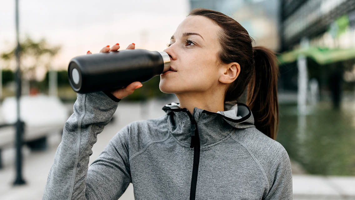 a woman drinks from a water bottle