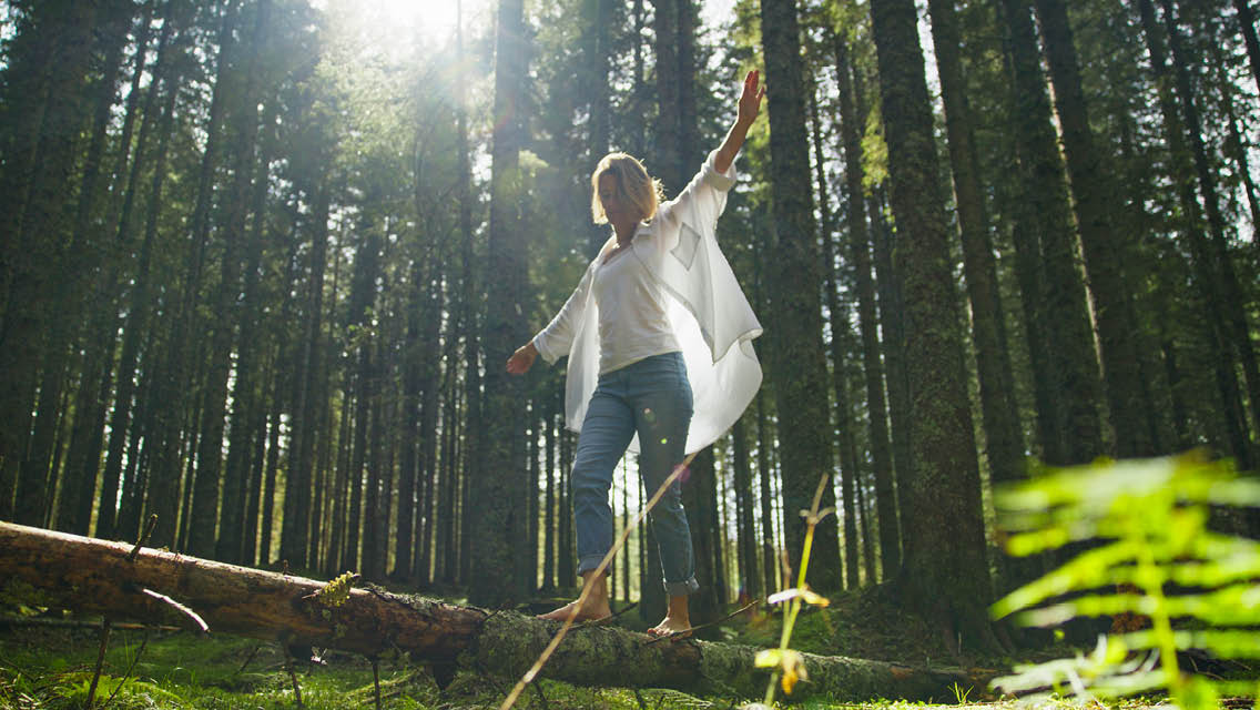 a woman balances walking across a fallen tree