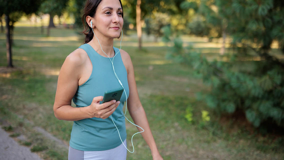a woman takes a walk while listening to music or a podcast