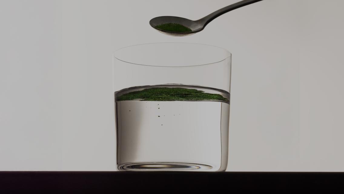 spoonful of supplement pouring into glass of water