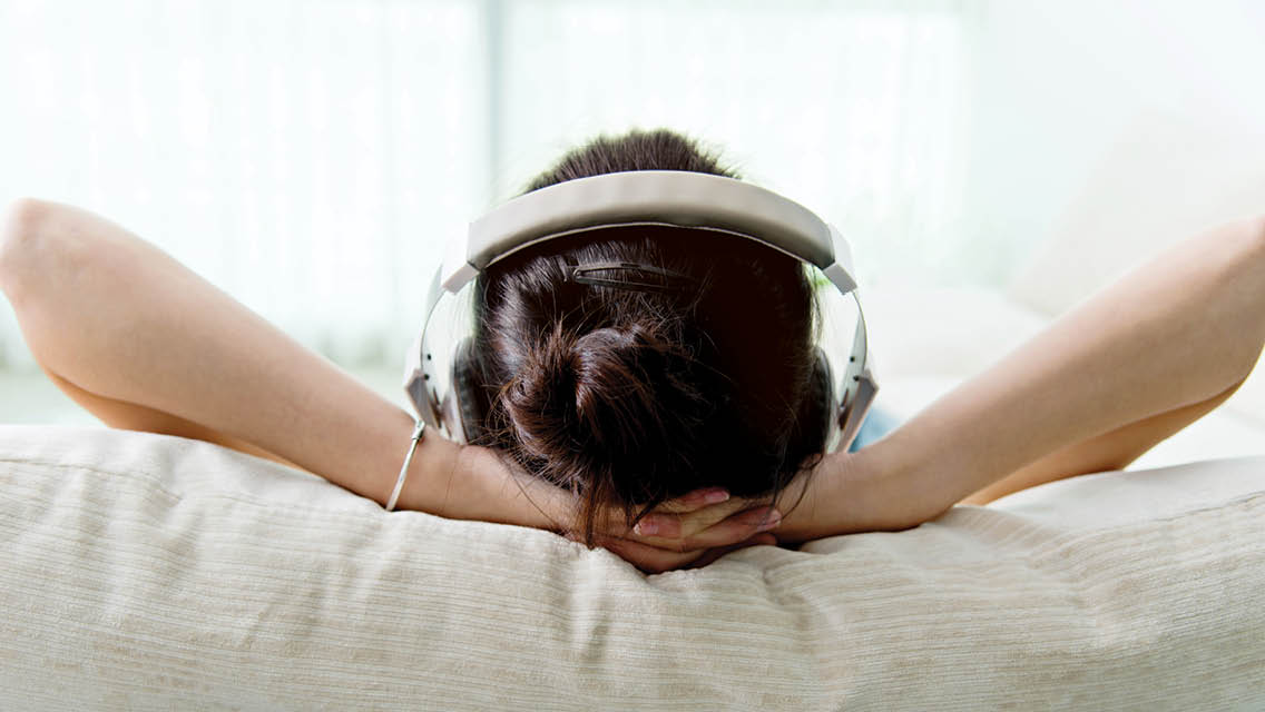 a person lies in bed listening to headphones