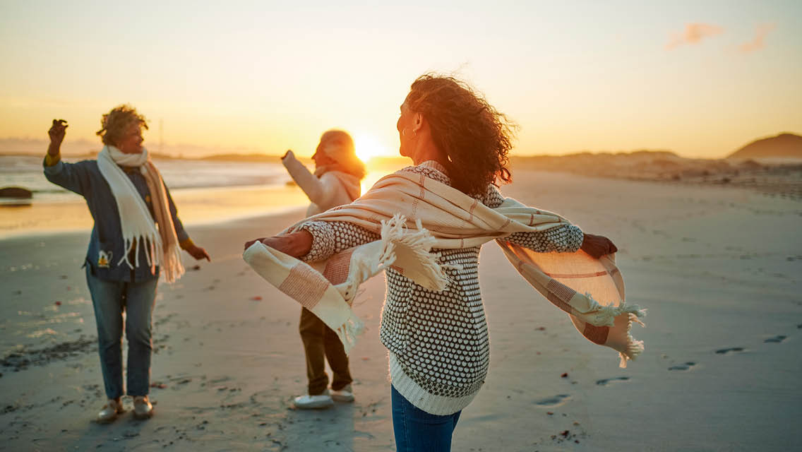 people dancing on a beach at sunset